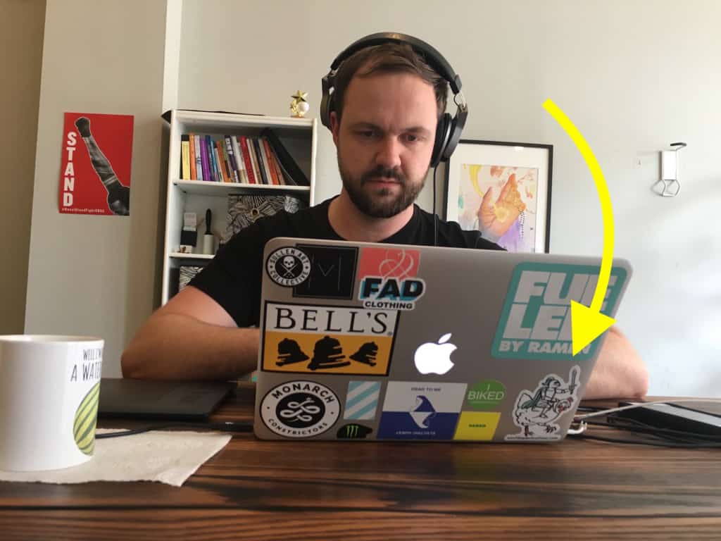 Corwin sits in the Next Day Animations office, looking at a macbook that is covered in stickers, One of them is Chicken Knight,