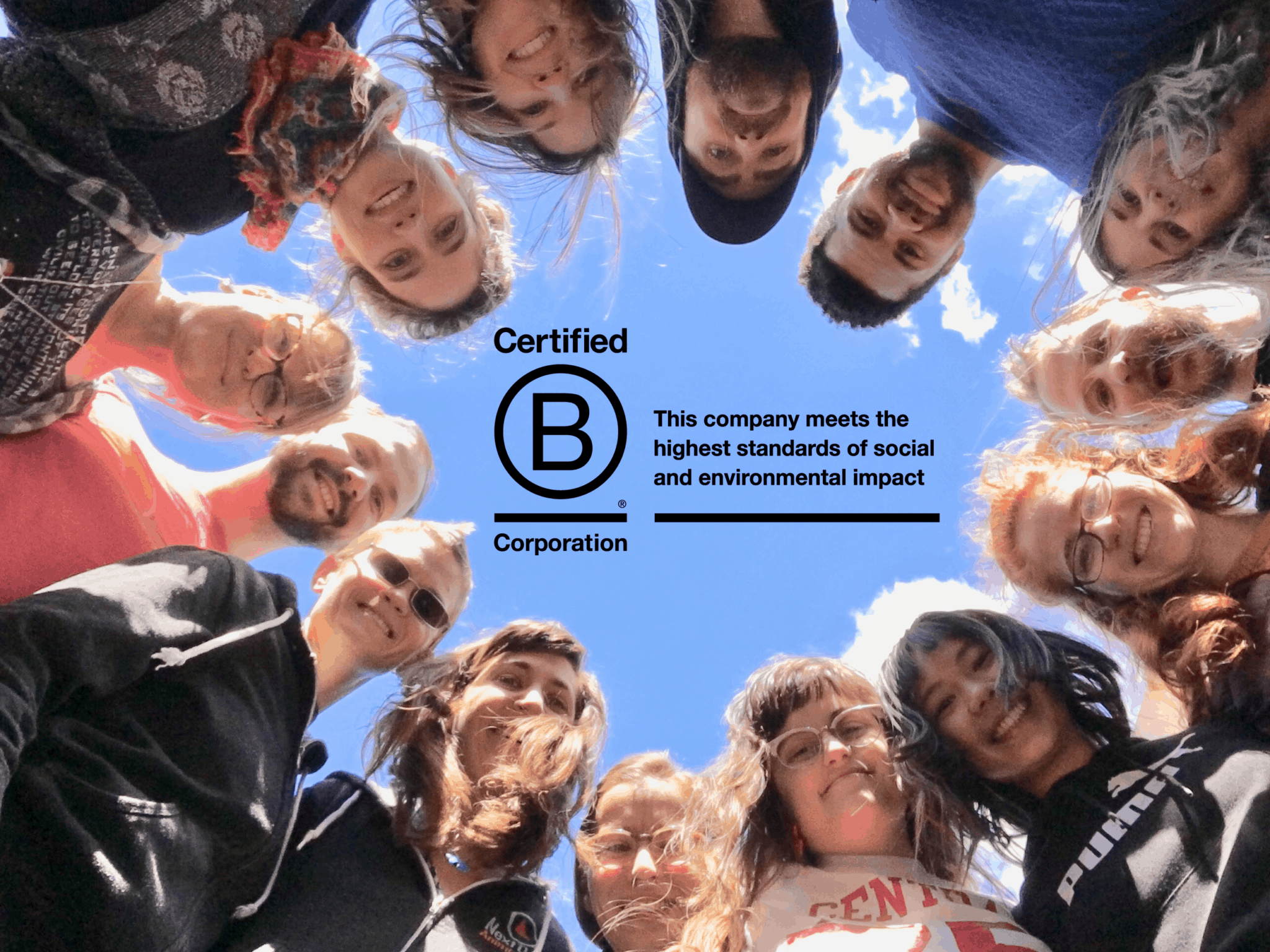 The NDA team smiles together in a portrait, taken from below them - their faces smile down from above with the BCorp logo in the center.