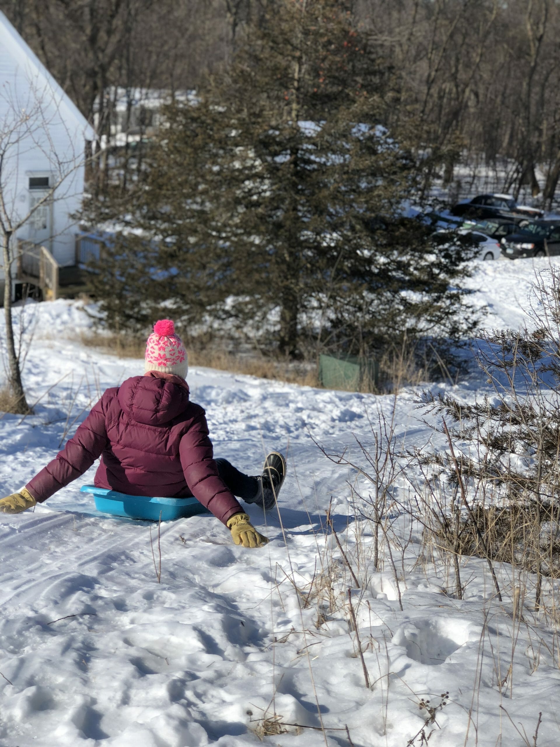 A person slides down a snowy hill on a sled